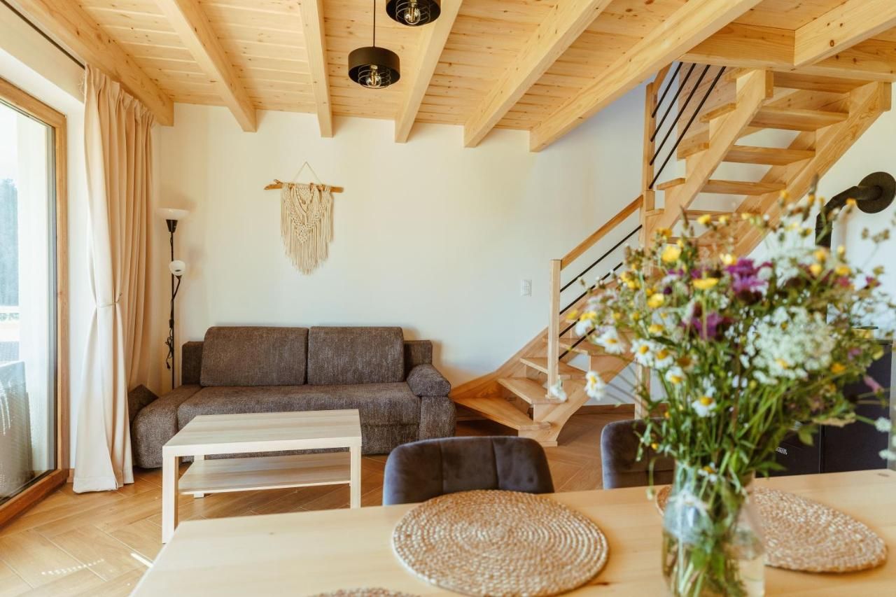 Salon z szarą sofą, drewnianymi belkami pod sufitem i schodami na piętro
